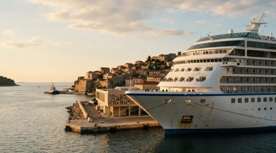 Cruise ship docked at coastal port with passengers on deck checking time during golden hour departure preparation