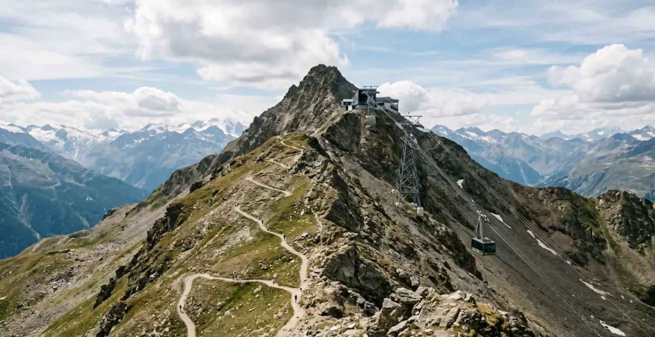 Expansive mountain panorama with dramatic elevation showing hiking trail and cable car infrastructure from aerial perspective